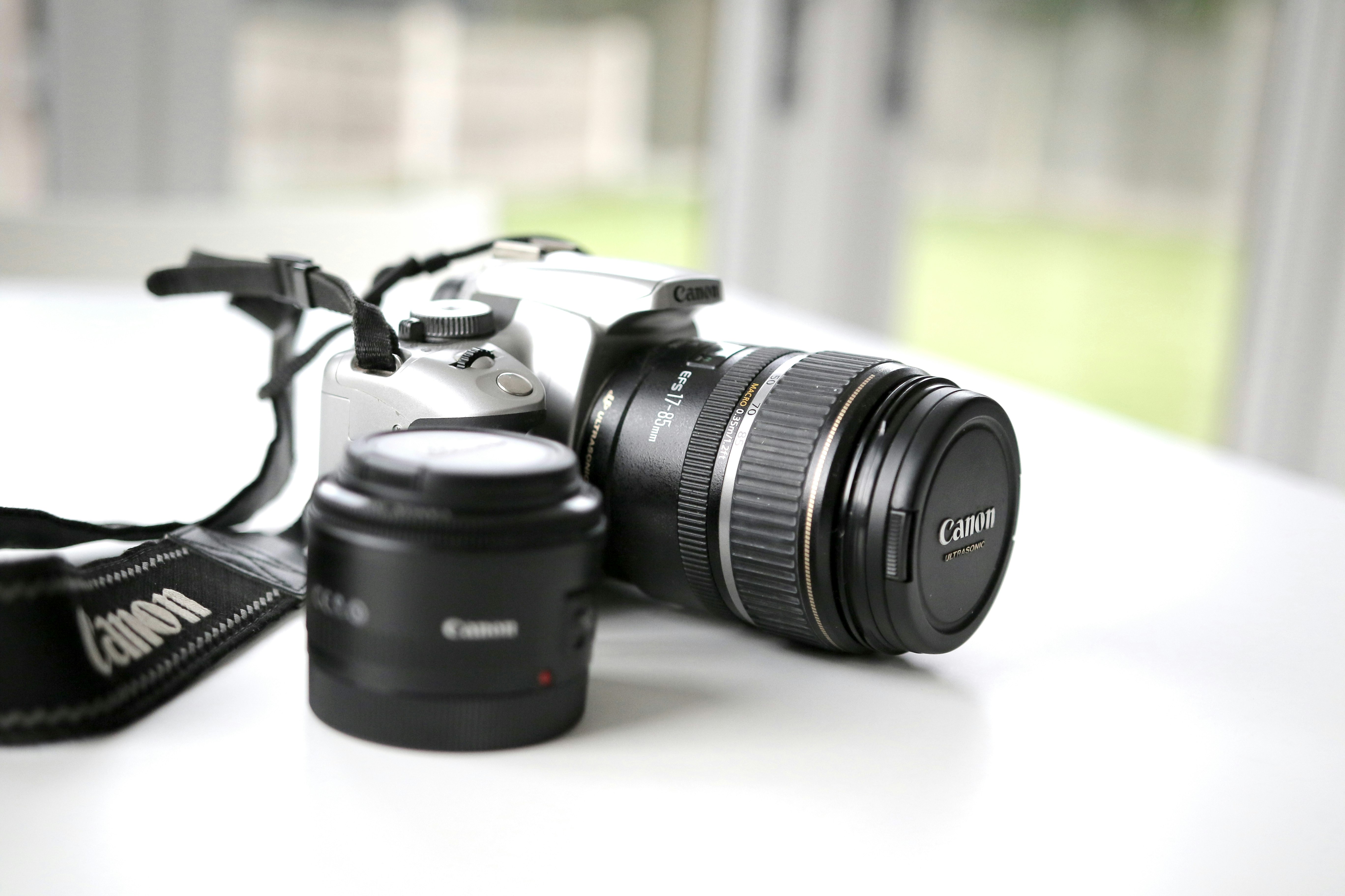 black Canon DSLR camera on white surface